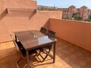 y balcón con mesa y sillas de madera. en Apartamentos Mar Azul, en Almerimar