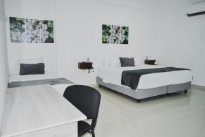 Habitación blanca con 2 camas y mesa en Hotel El Marqués De Manga, en Cartagena de Indias