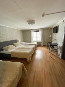 Säter的住宿－Säters Stadshotell，一间卧室设有三张床、一张桌子和一个窗户。
