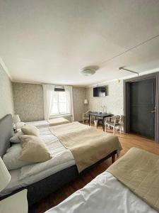1 dormitorio grande con 2 camas y mesa en Säters Stadshotell en Säter
