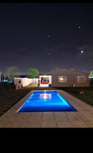 una gran piscina azul en un patio por la noche en Casa completa tipo campo. a 50 km de la capital Federal en General Rodríguez