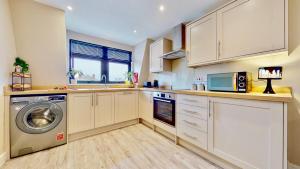a kitchen with white cabinets and a washer and dryer at Chatham Serviced Apartments by Hosty Lets in Chatham
