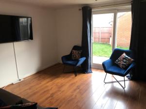 ein Wohnzimmer mit 2 Stühlen und einem Flachbild-TV in der Unterkunft Lovely 3 Bed Semi Detached house with off street parking located in a quiet Close in London