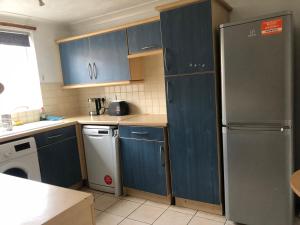 a kitchen with blue cabinets and a refrigerator at Lovely 3 Bed Semi Detached house with off street parking located in a quiet Close in London