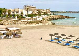 a beach with chairs and umbrellas and the ocean at Apartment Flamenca , Orihuela Costa in Orihuela