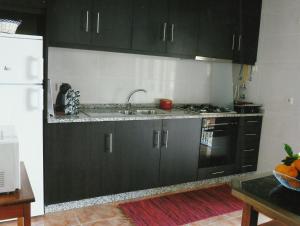 a kitchen with black cabinets and a sink and a refrigerator at Casa Quelhas in Besteiros