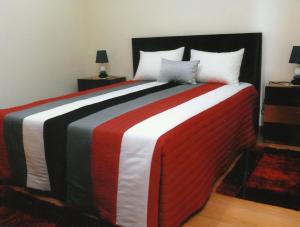 Casa Quelhas في Besteiros: سرير كبير وبطانية حمراء بيضاء وسوداء