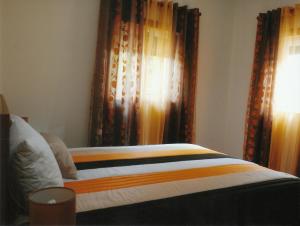a bed in a bedroom with curtains and a window at Casa Quelhas in Besteiros