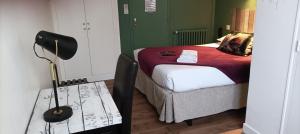 a bedroom with a bed and a lamp on a table at Hotel Le Petit Billot in Vitré