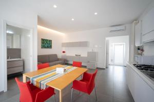 een keuken en een woonkamer met een tafel en rode stoelen bij WePuglia - Dimore Sarnelli in Polignano a Mare