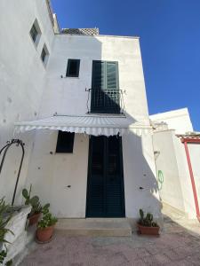 un edificio bianco con una porta verde e un tendone di Casa Borgo Monte a Otranto