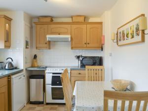 a kitchen with wooden cabinets and a table with chairs at Fernilea Cottage in Carbost