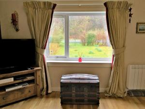 una sala de estar con una gran ventana con cortinas en Fernilea Cottage, en Carbost