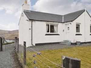 a white house with a fence in front of it at Fernilea Cottage in Carbost