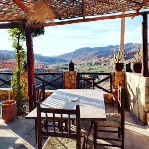 einen Tisch und Stühle auf einer Terrasse mit Aussicht in der Unterkunft Dar Isselday in Tisseldeï