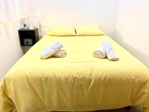 Una cama amarilla con toallas encima. en Adelfa - 2 hab, AA, parking gratis, junto Hospital en Murcia