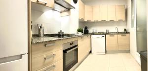 a kitchen with white appliances and wooden cabinets at Adelfa - 2 hab, AA, parking gratis, junto Hospital in Murcia
