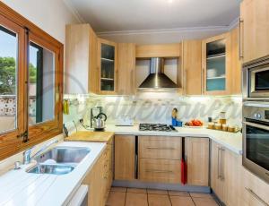 a kitchen with wooden cabinets and a sink at Villa Casablanca near port adriano by villasmediterranean in El Toro