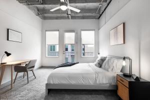 Schlafzimmer mit einem Bett, einem Schreibtisch und Fenstern in der Unterkunft Stylish City Living Apartments with Free Parking in Midtown Atlanta in Atlanta