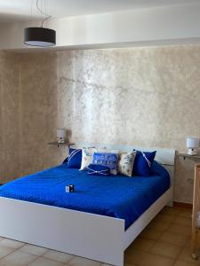 Schlafzimmer mit einem Bett mit blauer Bettwäsche und Kissen in der Unterkunft Vista mare center apartment in Tropea