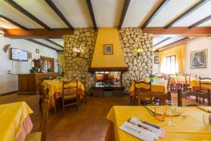 a restaurant with yellow tables and a fireplace at Albergo Dalla Mena in Romano D'Ezzelino