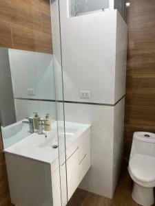 a white bathroom with a sink and a toilet at Apartamento Completo, cerca a Mall Aventura Plaza in Trujillo