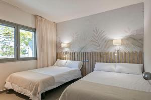 two beds in a room with two windows at Apartamentos Castellmar in Castelldefels