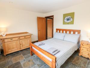 1 dormitorio con cama y tocador de madera en The Bike Shed, en Disley