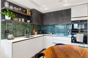 a kitchen with white cabinets and a wooden table at Stylish & Modern 1BR in Islington! in London