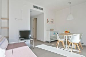 a living room with a table and chairs and a tv at Apartamentos Castellmar in Castelldefels