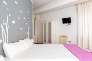 バルセロナにあるモンルームズ バルセロナのベッドルーム(紫の毛布を使用した大きな白いベッド付)