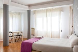 バルセロナにあるモンルームズ バルセロナのベッドルーム1室(紫の毛布が敷かれた大型ベッド1台付)