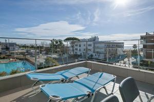 a balcony with blue chairs and a swimming pool at Apartamentos Castellmar in Castelldefels