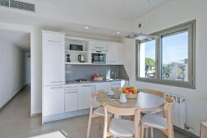 una cocina con mesa y sillas y una cocina con armarios blancos. en Apartamentos Castellmar, en Castelldefels