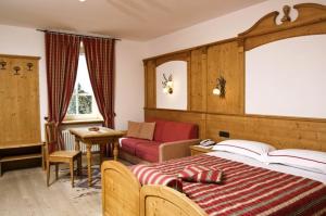 a bedroom with a bed and a couch and a table at Locanda Alpina in Brez