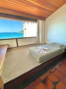 a large bed in a room with a large window at Orlanova Hotel in Arraial do Cabo