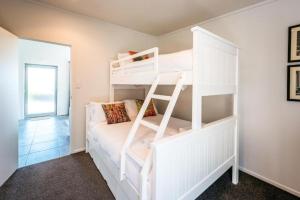 a bedroom with two bunk beds with a ladder at Delamore Cove - Kowhai - Waiheke Escapes in Matiatia Bay
