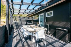 a table and chairs on a patio with a pergola at Delamore Cove - Kowhai - Waiheke Escapes in Matiatia Bay
