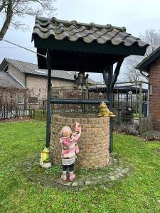 Une petite fille debout devant une maison d'oiseaux dans l'établissement b&b de Wensput, à De Moer