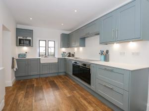 cocina con armarios azules y suelo de madera en Kylemore Railway Cottage, en Stamford