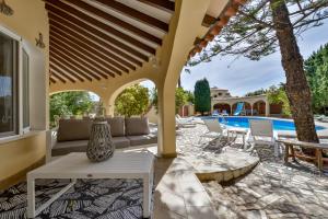 a patio with a couch and tables and a pool at Villas Guzman - Xenia in Calpe