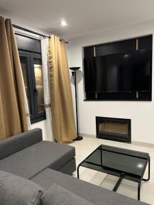 uma sala de estar com um sofá e uma televisão de ecrã plano em Villa Zeus em Rota