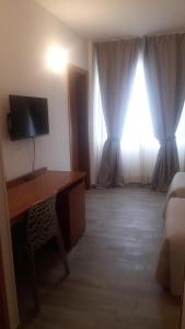 um quarto com uma secretária, uma televisão e uma janela em Toscana Ambassador em Poggibonsi