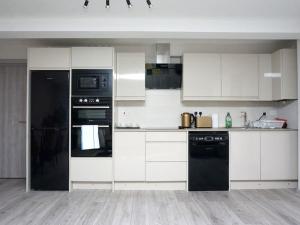 uma cozinha com armários brancos e electrodomésticos pretos em Horizon House, Stunning 2-Bedroom Flat 1, Parking, Netflix, Oxford em Oxford