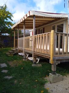 a wooden house with a porch on the grass at Joli mobil-home pour 8 personnes tout confort 3 chambres vue étang avec piscine in Onzain