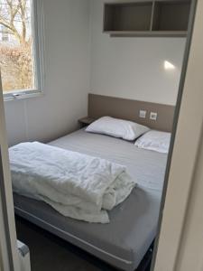 two beds in a small room with a window at Joli mobil-home pour 8 personnes tout confort 3 chambres vue étang avec piscine in Onzain