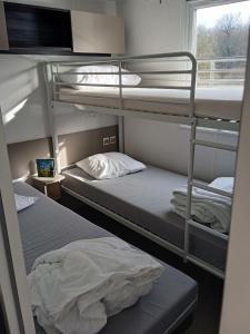 two bunk beds in a room with a window at Joli mobil-home pour 8 personnes tout confort 3 chambres vue étang avec piscine in Onzain