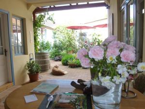 una mesa con un jarrón lleno de flores rosas y blancas en Stieglerhof Apartments Dr Eitner GnbR Bernd und Edeltrud, en Illmitz