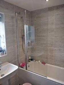 a bathroom with a shower and a tub and a sink at Chandra House in Swindon