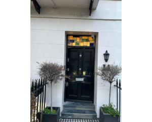 una puerta negra en una casa blanca con plantas en Victoria Square, en Londres